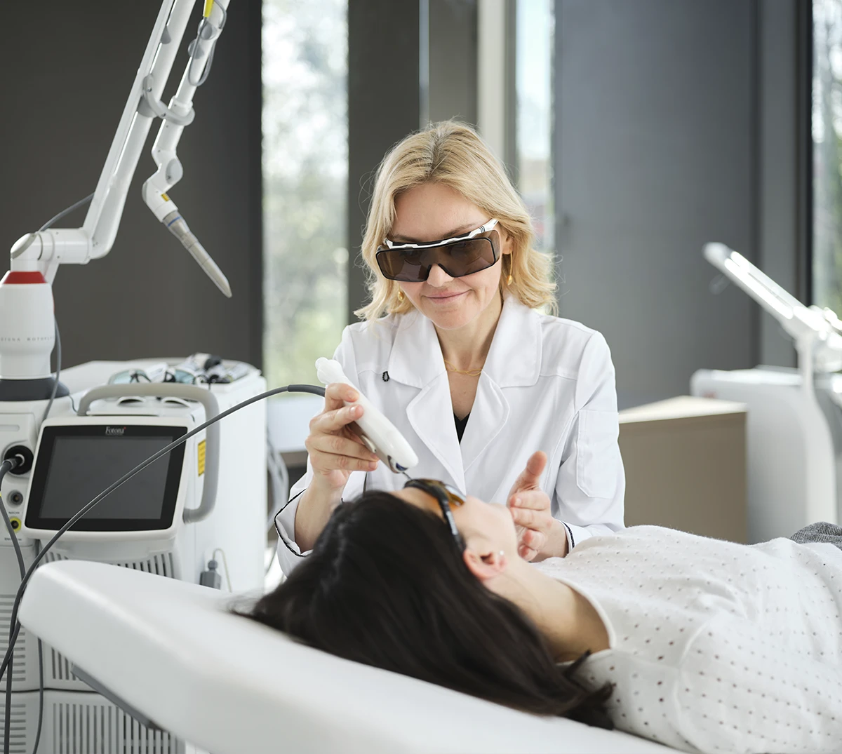 doctor wearing safety glasses is working with laser on patient's face